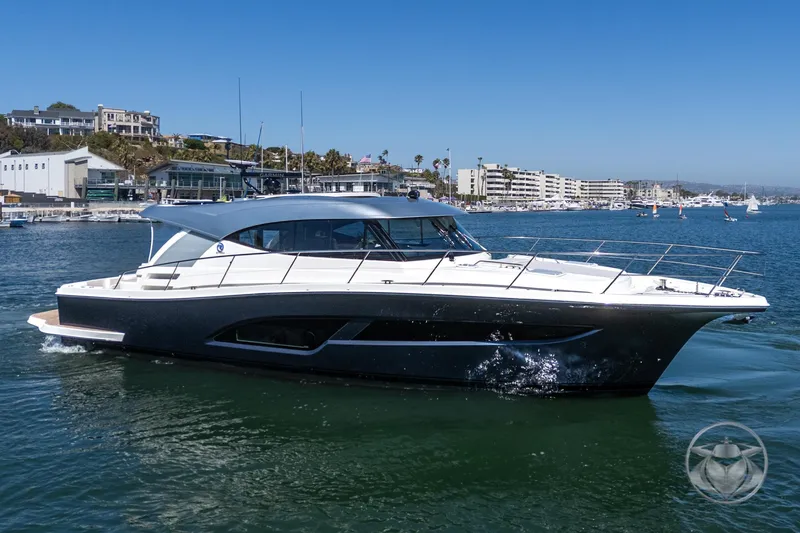 Slide: The Image of 2025 Riviera 465 SUV yacht cruising in a marina under clear blue skies. - 14