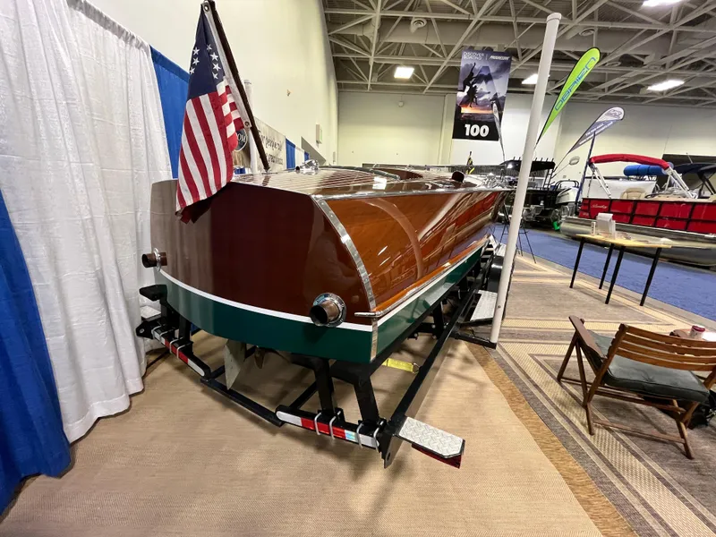 Slide: The Image of 1932 Hacker-Craft Triple Cockpit boat displayed indoors with American flag. - 21