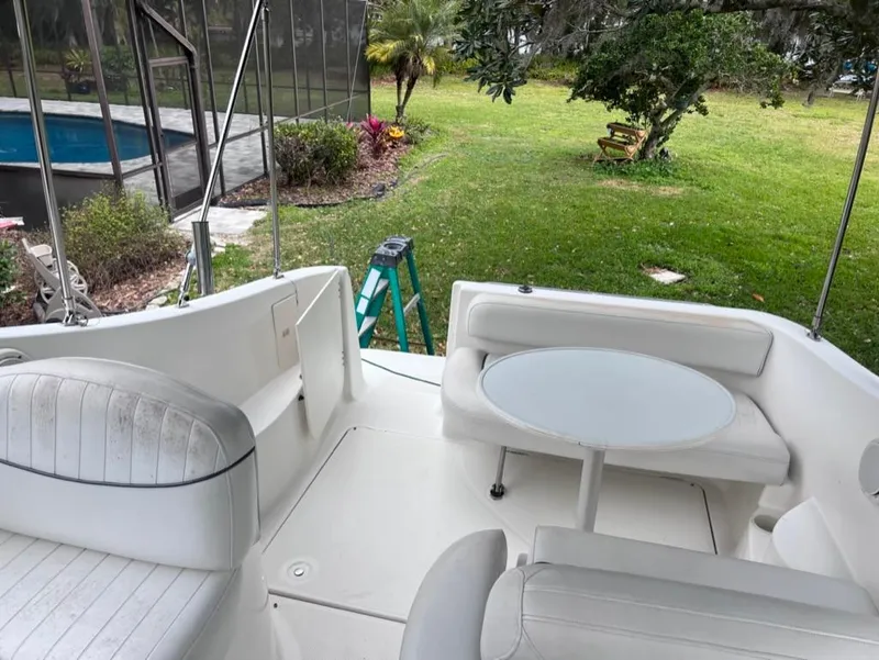 Slide: The Image of 2005 Maxum 2500 SCR boat interior with seating and table, near a pool and garden. - 12