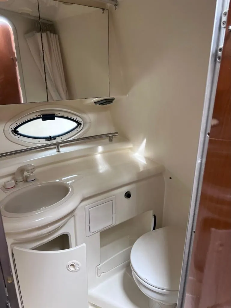 Slide: The Image of Compact bathroom in a 2005 Maxum 2500 SCR boat with sink, toilet, and mirror. - 13