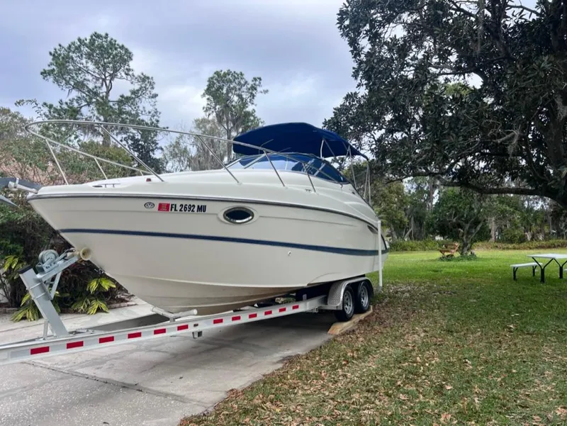 Slide: The Image of 2005 Maxum 2500 SCR boat on a trailer in a lush, green yard. - 2