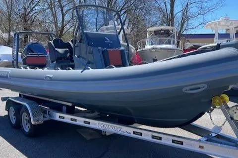 Slide: The Image of 2024 Highfield Sport 660 boat on trailer, parked outdoors. - 2