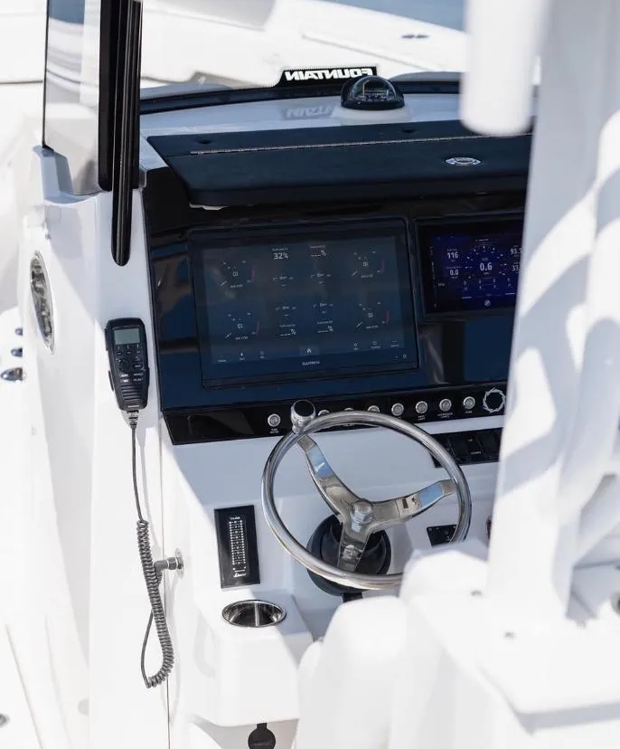 Slide: The Image of 2024 Fountain Bluewater 38 Tournament Edition boat dashboard with steering wheel and electronic controls. - 14