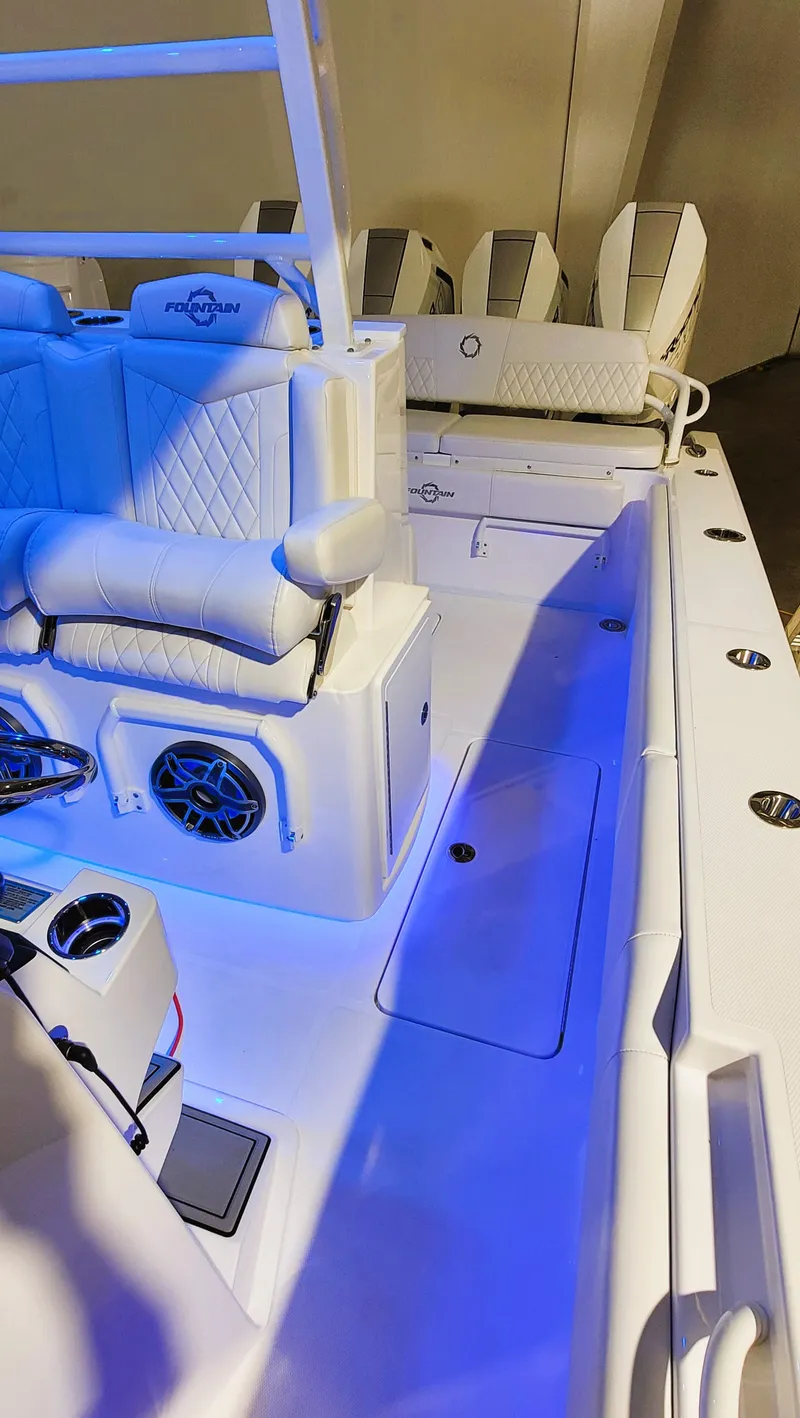 Slide: The Image of 2024 Fountain Bluewater 38 Tournament Edition boat interior with blue lighting and seating. - 37