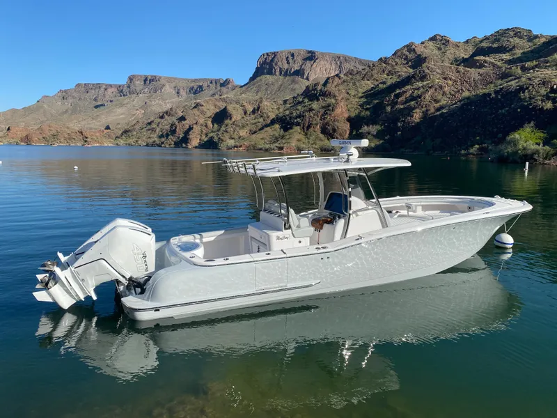 The Image of 2026 Mag Bay 33 CC boat on a serene lake with mountainous backdrop. - 0