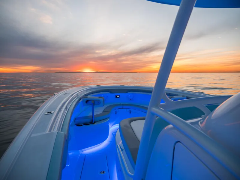 Slide: The Image of Mag Bay 33 CC 2025 boat with blue interior lights at sunset on the water. - 13