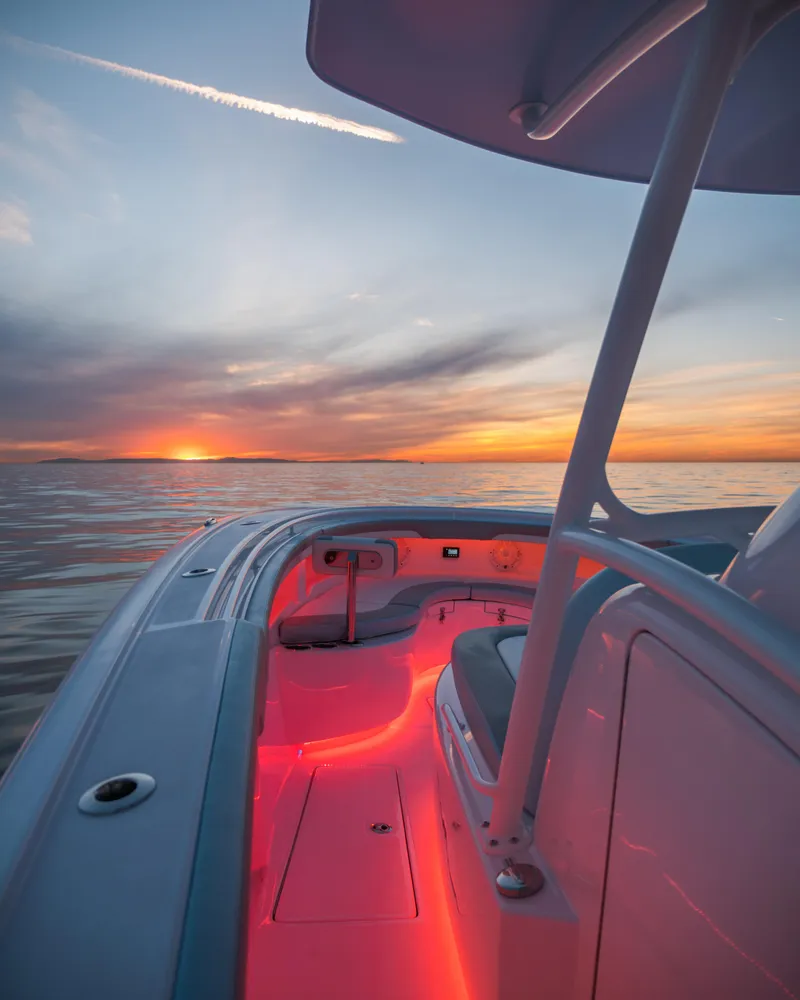 Slide: The Image of 2025 Mag Bay 33 CC boat at sunset with red deck lighting. - 17