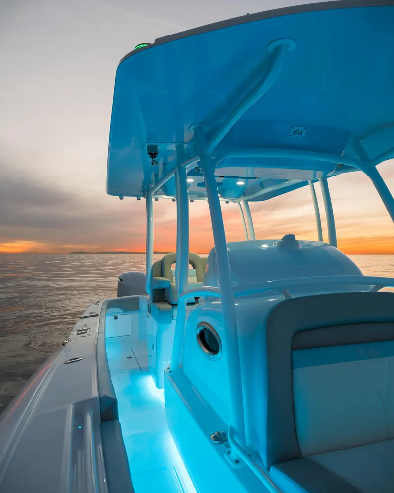 Slide: The Image of 2025 Mag Bay 33 CC boat at sunset with blue interior lighting. - 25