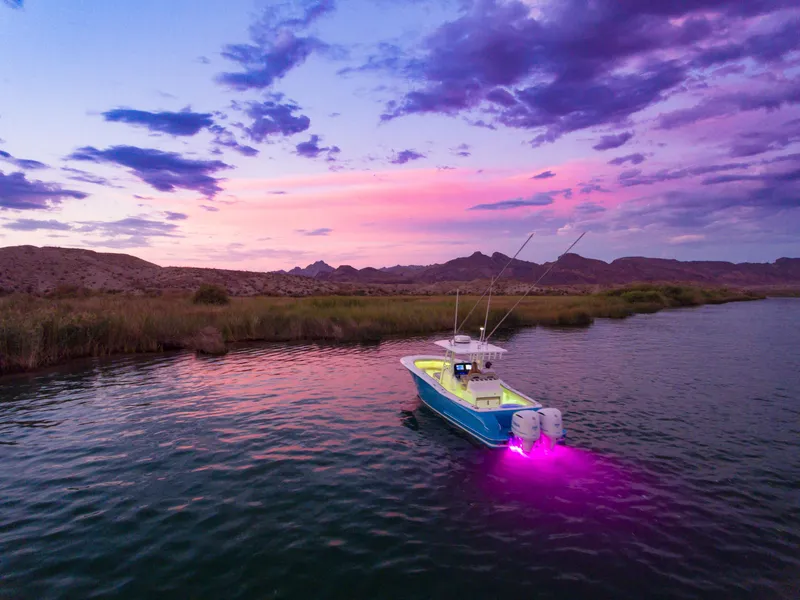 Slide: The Image of Mag Bay 33 CC 2025 boat on serene lake at sunset with purple underwater lights. - 43