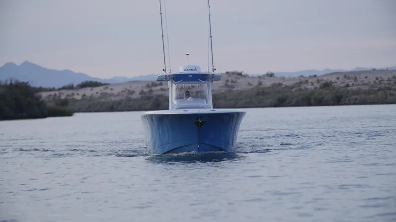 Slide: The Image of 2025 Mag Bay 33 CC boat cruising on a calm lake with mountains in the background. - 46