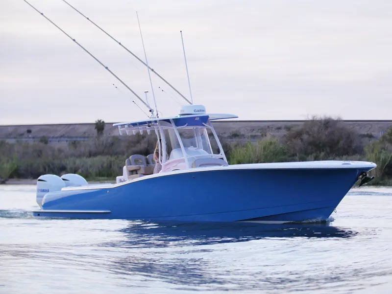 Slide: The Image of 2025 Mag Bay 33 CC boat on water, blue hull, twin engines, fishing rods. - 50
