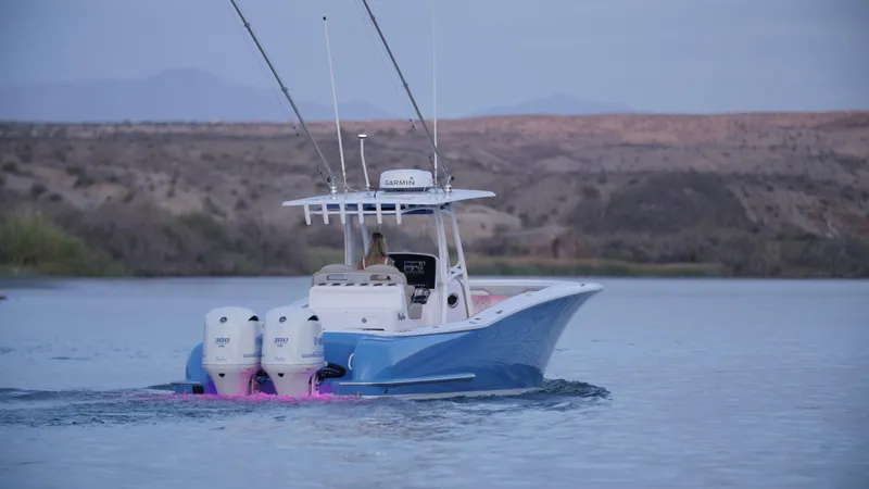 Slide: The Image of 2025 Mag Bay 33 CC boat cruising on a calm lake with scenic background. - 51
