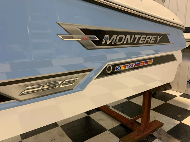 Slide: The Image of 2023 Monterey 298 Super Sport boat side view with logo and nautical flags. - 1