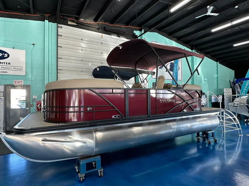 The Image of 2025 Sylvan Mirage X1 pontoon boat displayed indoors on a blue floor. - 0