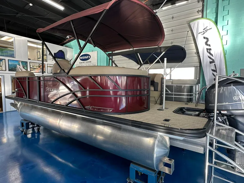 Slide: The Image of 2025 Sylvan Mirage X1 pontoon boat in showroom, featuring sleek design and maroon exterior. - 3