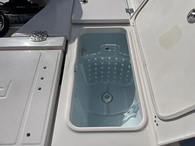Slide: The Image of 2023 Robalo 266 Cayman livewell compartment with open lid. - 11