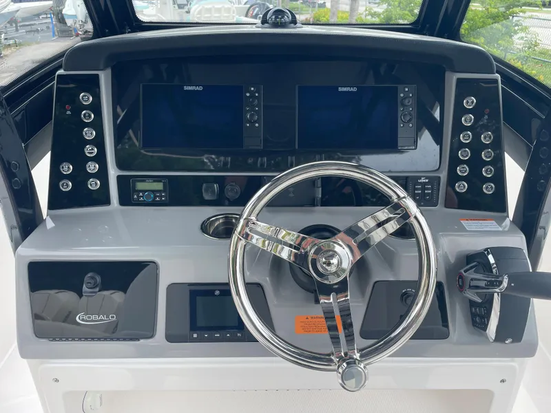 Slide: The Image of 2023 Robalo 266 Cayman boat dashboard with dual Simrad displays and steering wheel. - 5
