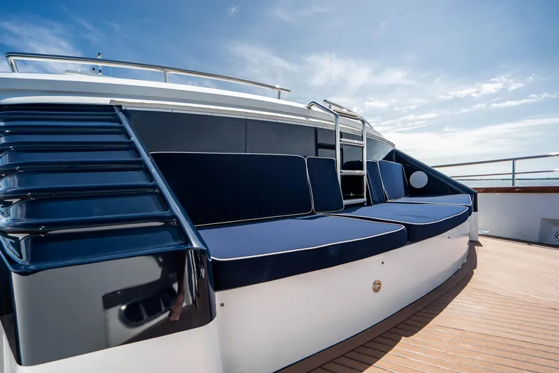 Slide: The Image of 1989 Broward Tri-Deck yacht with blue cushioned seating on deck. - 31