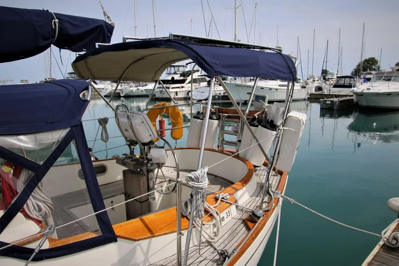 Slide: The Image of 1986 Mason 33 sailboat docked in marina, featuring blue canopy and wooden accents. - 10