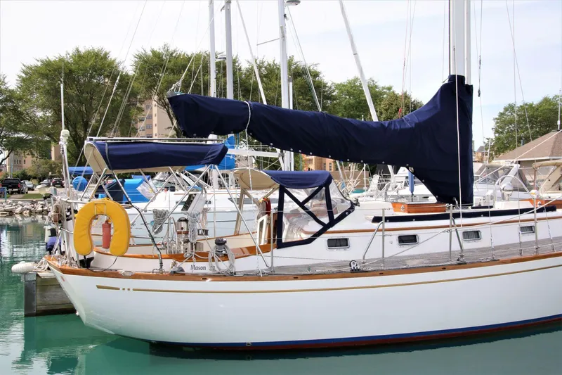 Slide: The Image of 1986 Mason 33 sailboat docked in marina, featuring blue covers and white hull. - 11