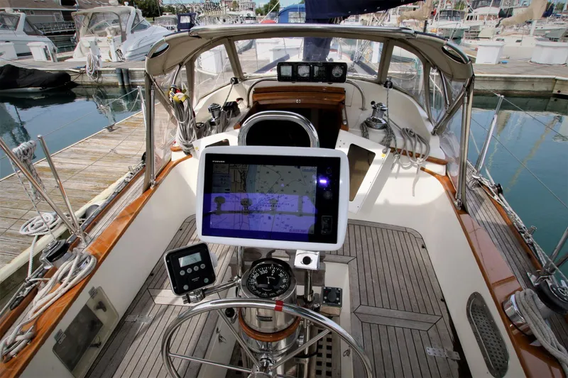 Slide: The Image of 1986 Mason 33 sailboat cockpit with navigation equipment and wooden deck, docked at marina. - 17