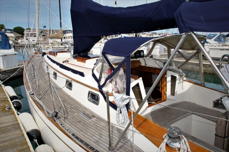 Slide: The Image of 1986 Mason 33 sailboat docked at marina, featuring wooden deck and blue canopy. - 22
