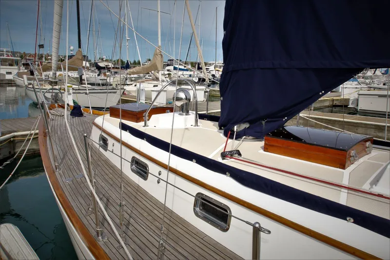 Slide: The Image of 1986 Mason 33 sailboat docked in a marina, featuring wooden deck and blue sail cover. - 23