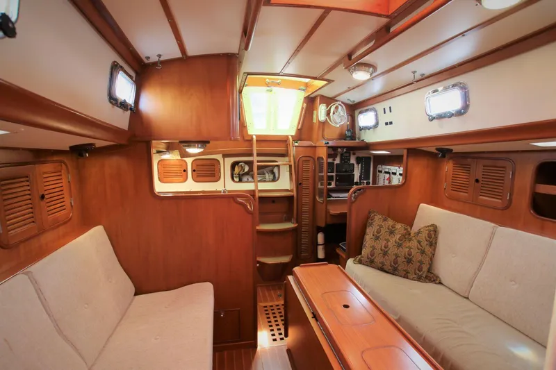 Slide: The Image of Interior of a 1986 Mason 33 sailboat, featuring wooden paneling and cozy seating. - 30