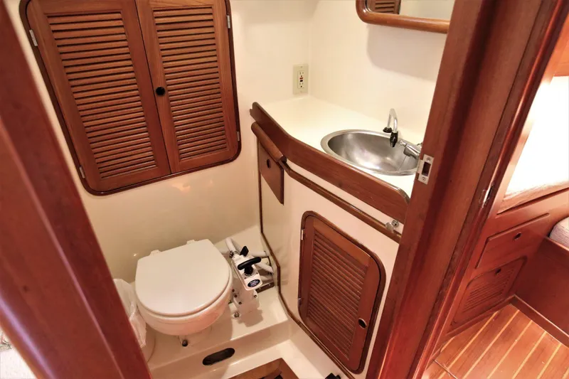 Slide: The Image of 1986 Mason 33 yacht bathroom with wooden cabinets, sink, and toilet. - 38