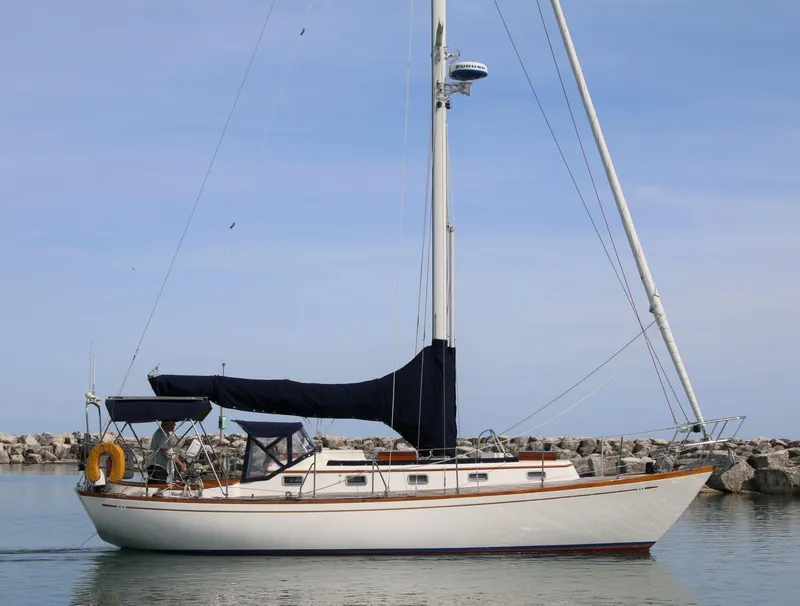 Slide: The Image of 1986 Mason 33 sailboat docked in calm waters, featuring a sleek design and black sail cover. - 5