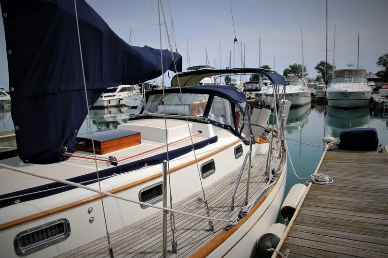 Slide: The Image of Sailboat docked at marina, Mason 33 model, 1986, with blue canopy and wooden deck. - 9