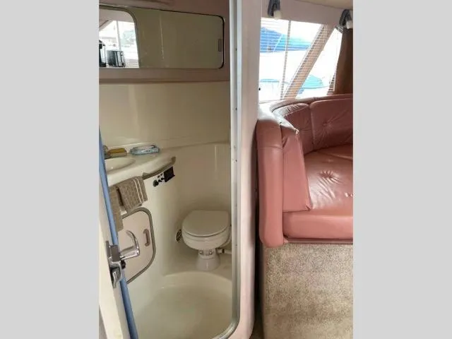 Slide: The Image of 1989 Sea Ray 300 Sedan Bridge interior with bathroom and seating area. - 17