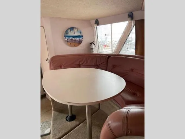 Slide: The Image of 1989 Sea Ray 300 Sedan Bridge interior dining area with round table and red leather seating. - 18