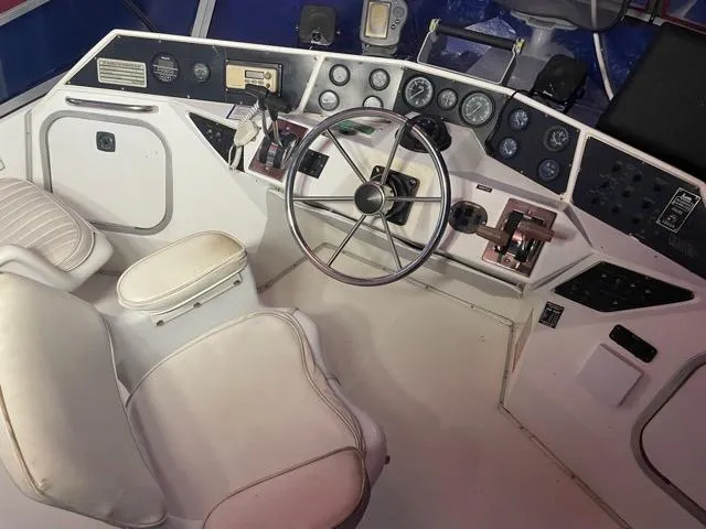 Slide: The Image of 1989 Sea Ray 300 Sedan Bridge helm with steering wheel, gauges, and captain's chair. - 9