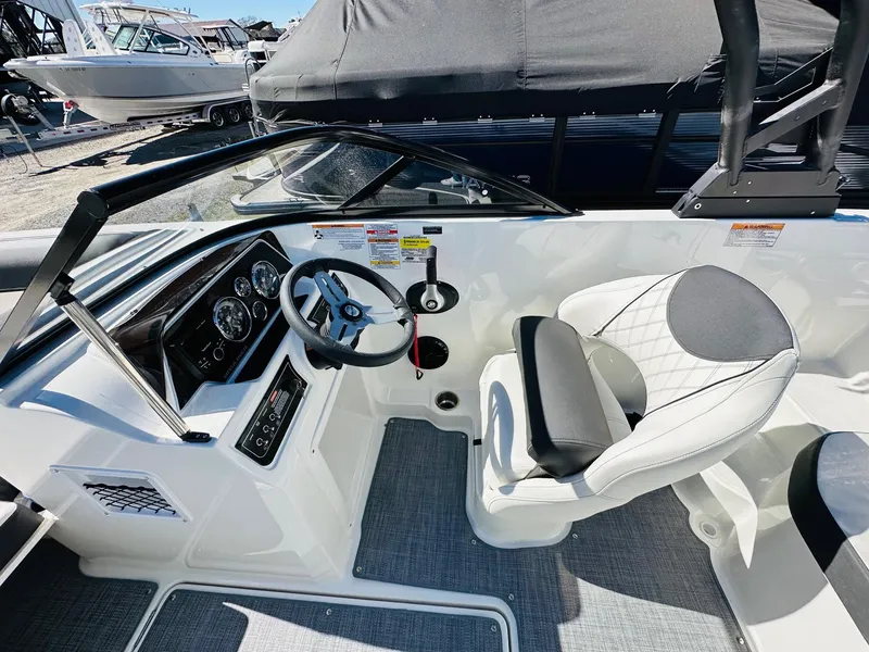 Slide: The Image of 2023 Bayliner DX 2050 boat cockpit with steering wheel and captain's chair. - 11