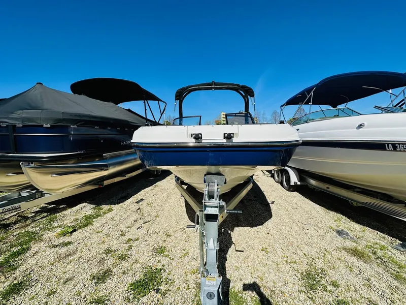 Slide: The Image of 2023 Bayliner DX 2050 boat on a trailer, front view, parked between other boats. - 3
