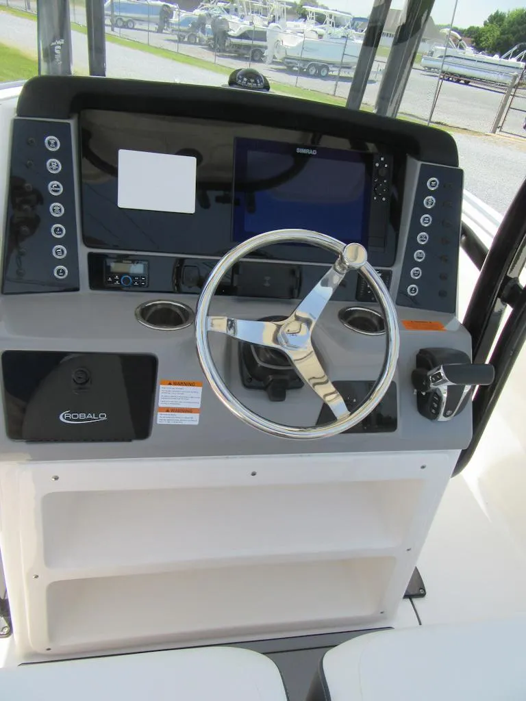 Slide: The Image of 2023 Robalo R230 Center Console boat helm with steering wheel and navigation controls. - 14