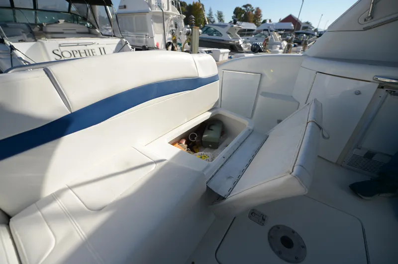 Slide: The Image of 2007 Formula 34 PC boat interior with open storage compartment, white seating, and marina background. - 36