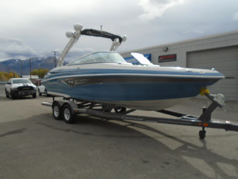 Slide: The Image of 2022 Crownline 240 SS boat on a trailer in a parking lot. - 2