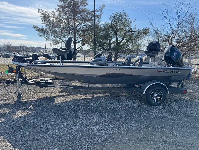 Slide: The Image of 2023 Vexus AVX181 boat on trailer, parked outdoors, with trees in background. - 0