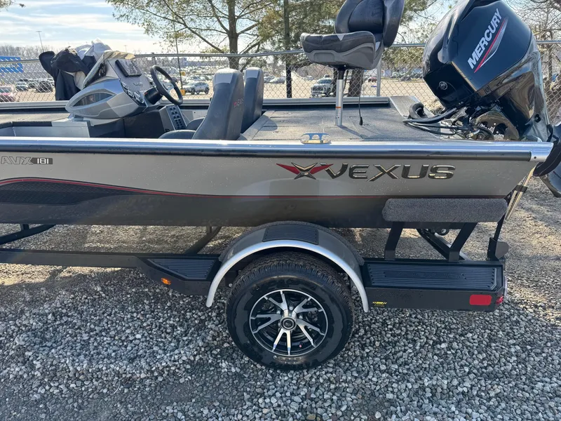 Slide: The Image of 2023 Vexus AVX181 boat with Mercury engine on a trailer, parked on gravel. - 23