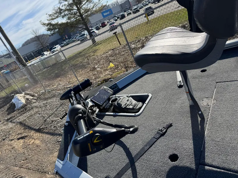 Slide: The Image of 2023 Vexus AVX181 boat deck with seat and trolling motor, parked near a fence. - 9