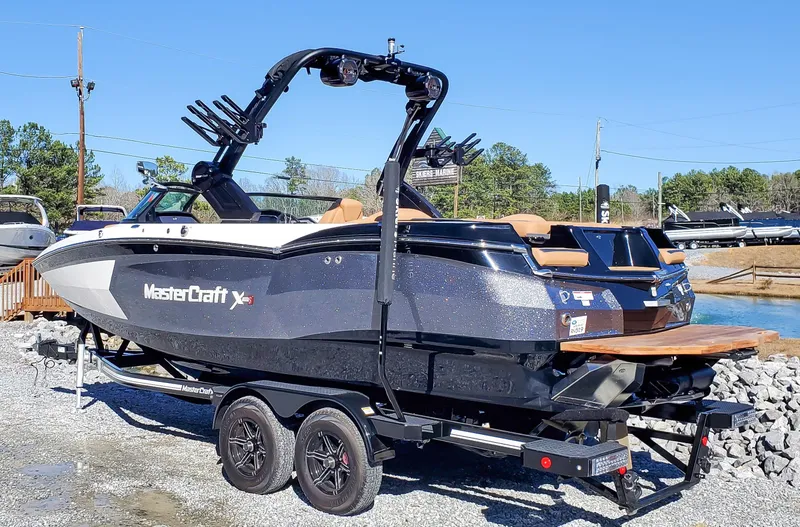 Slide: The Image of 2022 MasterCraft XStar boat on a trailer by the water. - 1
