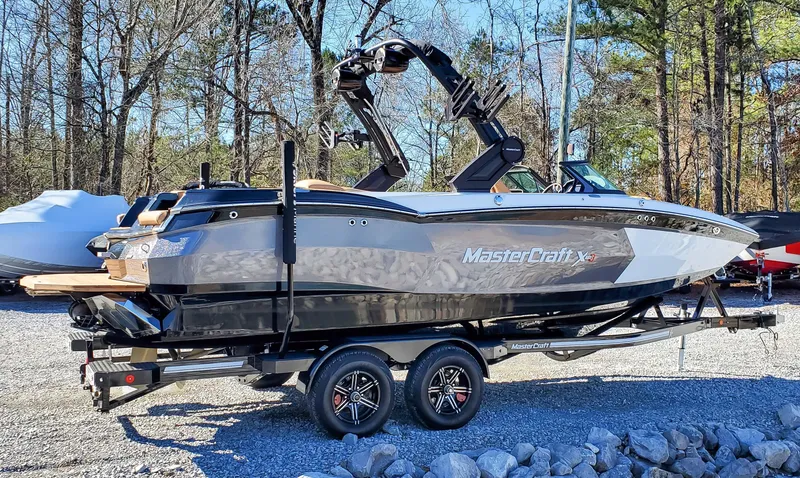 Slide: The Image of 2022 MasterCraft XStar boat on a trailer in a wooded area. - 3