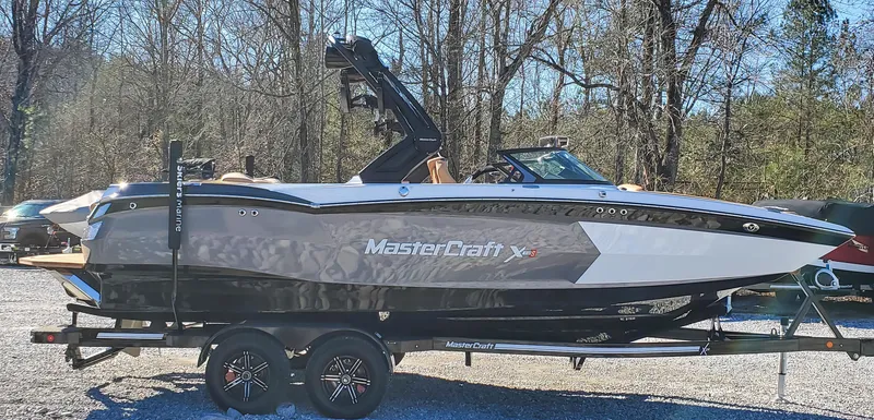 Slide: The Image of 2022 MasterCraft XStar boat on a trailer in a wooded area. - 4