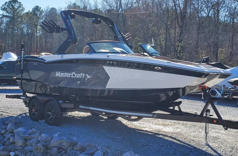 Slide: The Image of 2022 MasterCraft XStar boat on a trailer in a wooded area. - 5