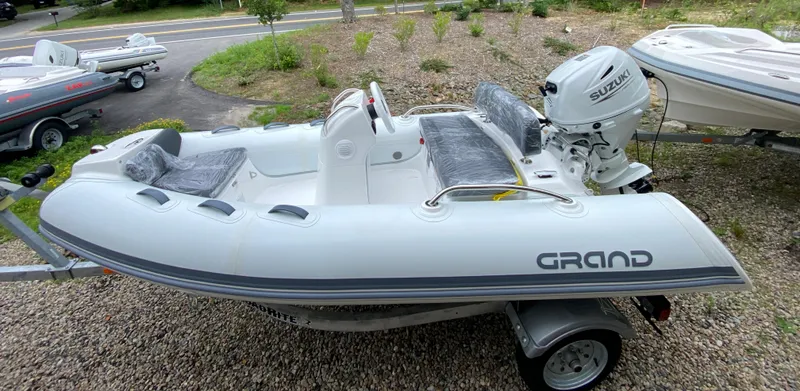 The Image of 2023 Grand G 340 inflatable boat with Suzuki DF25ATSW outboard motor on trailer. - 0