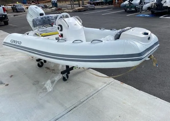 Slide: The Image of 2023 Grand G 340 inflatable boat with DF25ATSW outboard motor in a parking lot. - 3