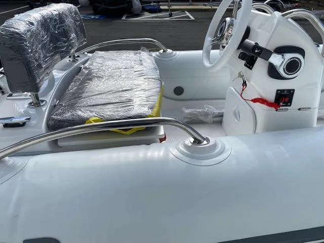 Slide: The Image of 2023 Grand G 340 w/ DF25ATSW inflatable boat interior, featuring steering console and cushioned seating. - 7