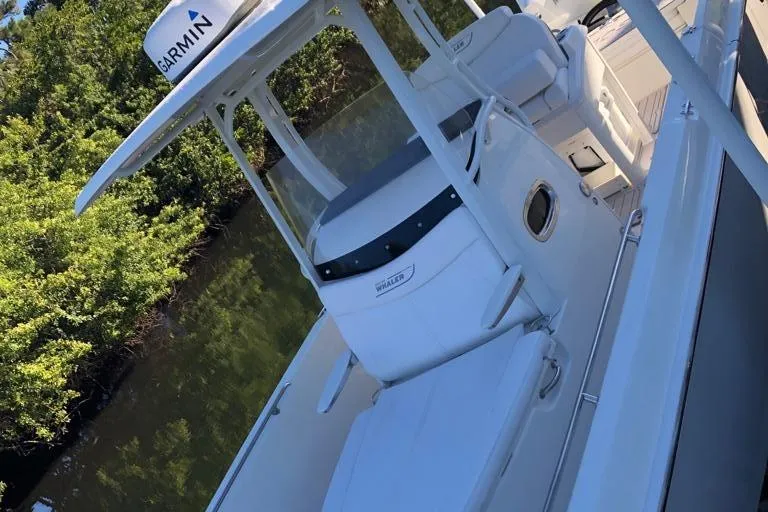 Slide: The Image of 2021 Boston Whaler Dauntless 27 boat with Garmin radar, docked near lush greenery. - 10